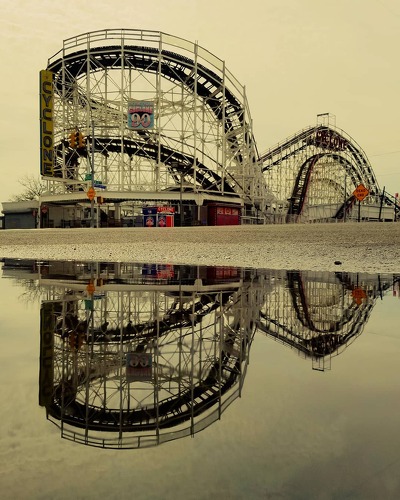 photograph and reflection of a cyclone amusement park ride