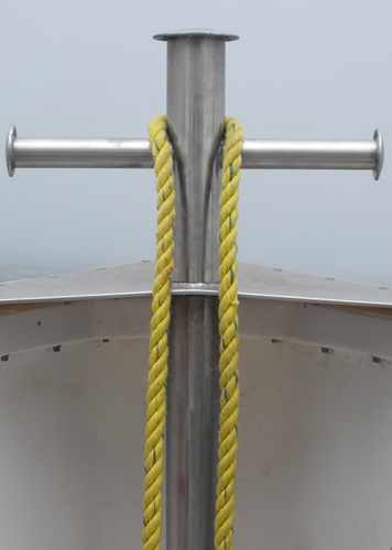 bow of boat with yellow rope on a steel cross on a foggy day at sea