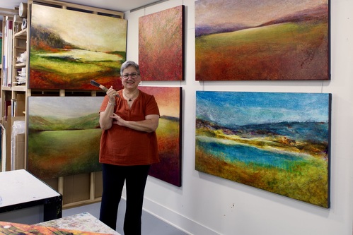 Artist Lori Latham in her studio with paintings