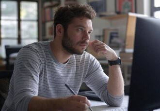 A young man in an art studio writing an email