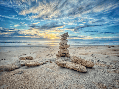 fine art photo of stacked rocks on a beach with sunset